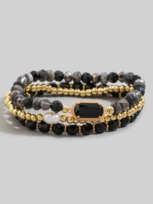 Set of beaded bracelets with gold accents on a gray background