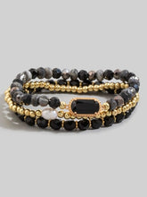 Set of beaded bracelets with gold accents on a gray background