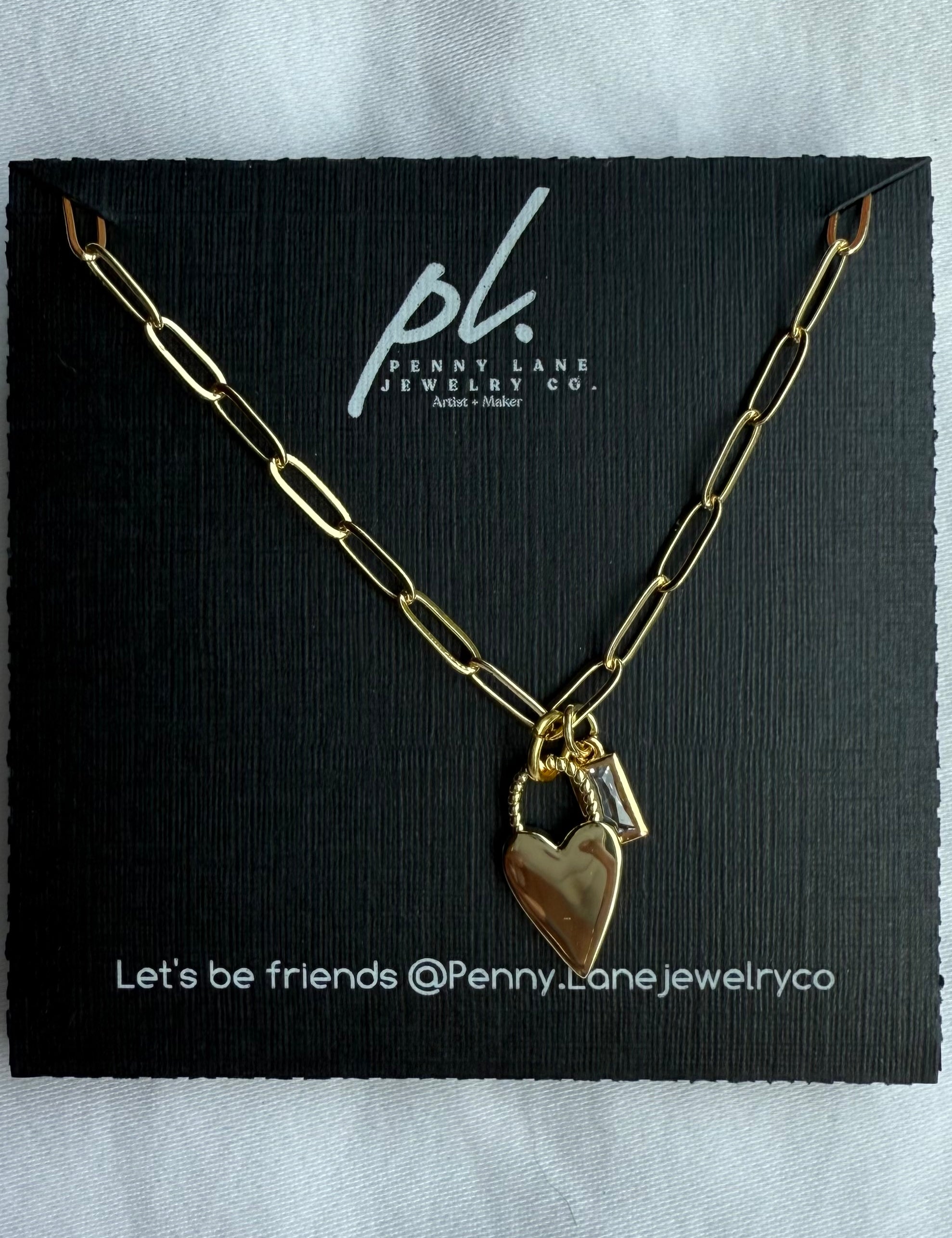 Gold chain necklace with a heart pendant on a Penny Lane Jewelry Co card.