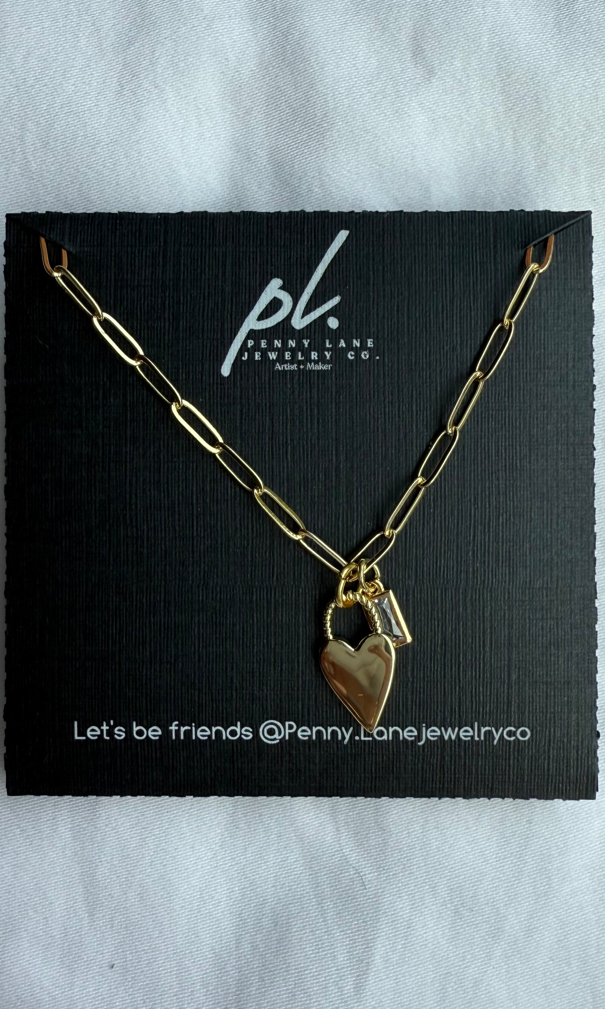 Gold chain necklace with a heart pendant on a Penny Lane Jewelry Co card.