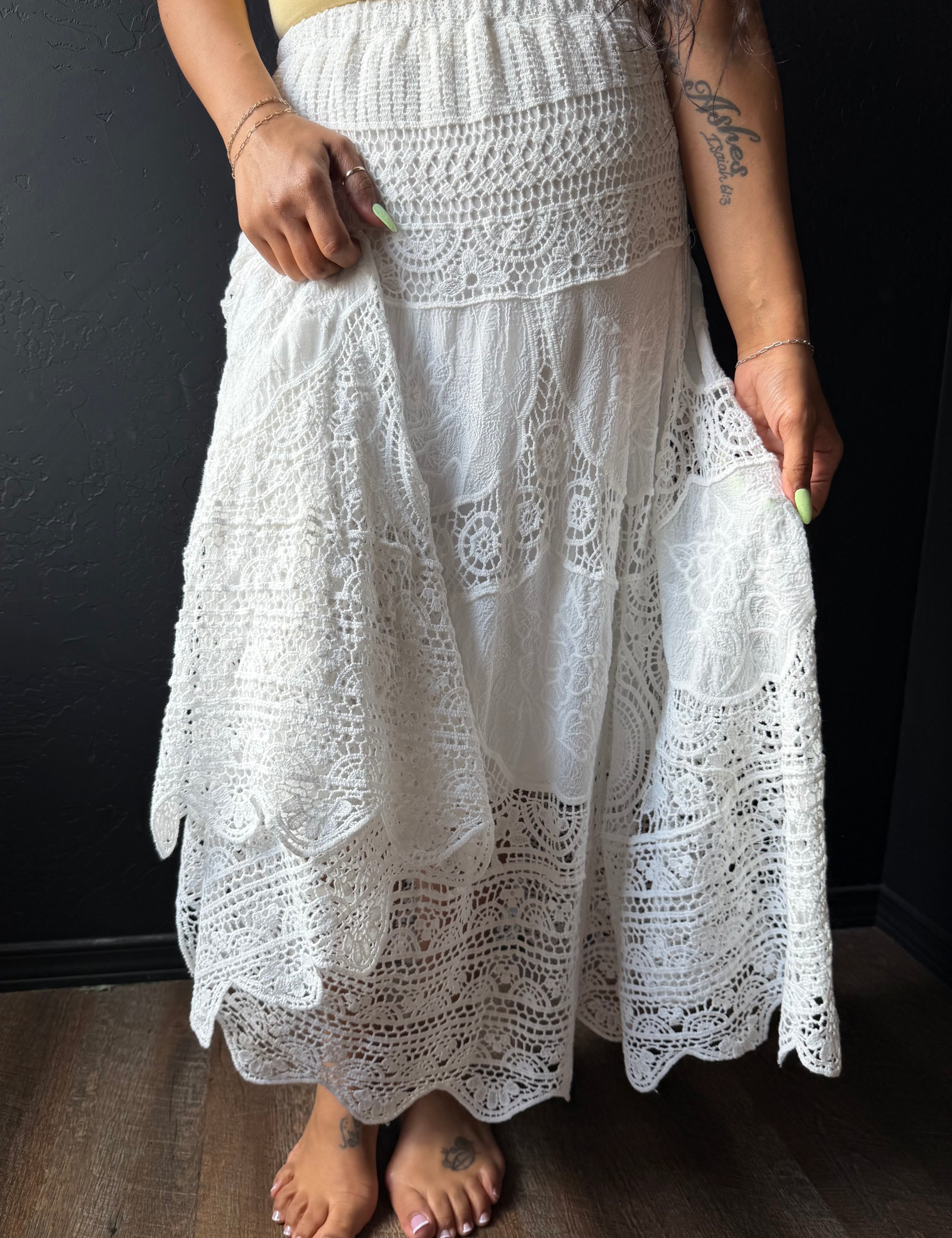 White lace skirt worn by a person against a dark background