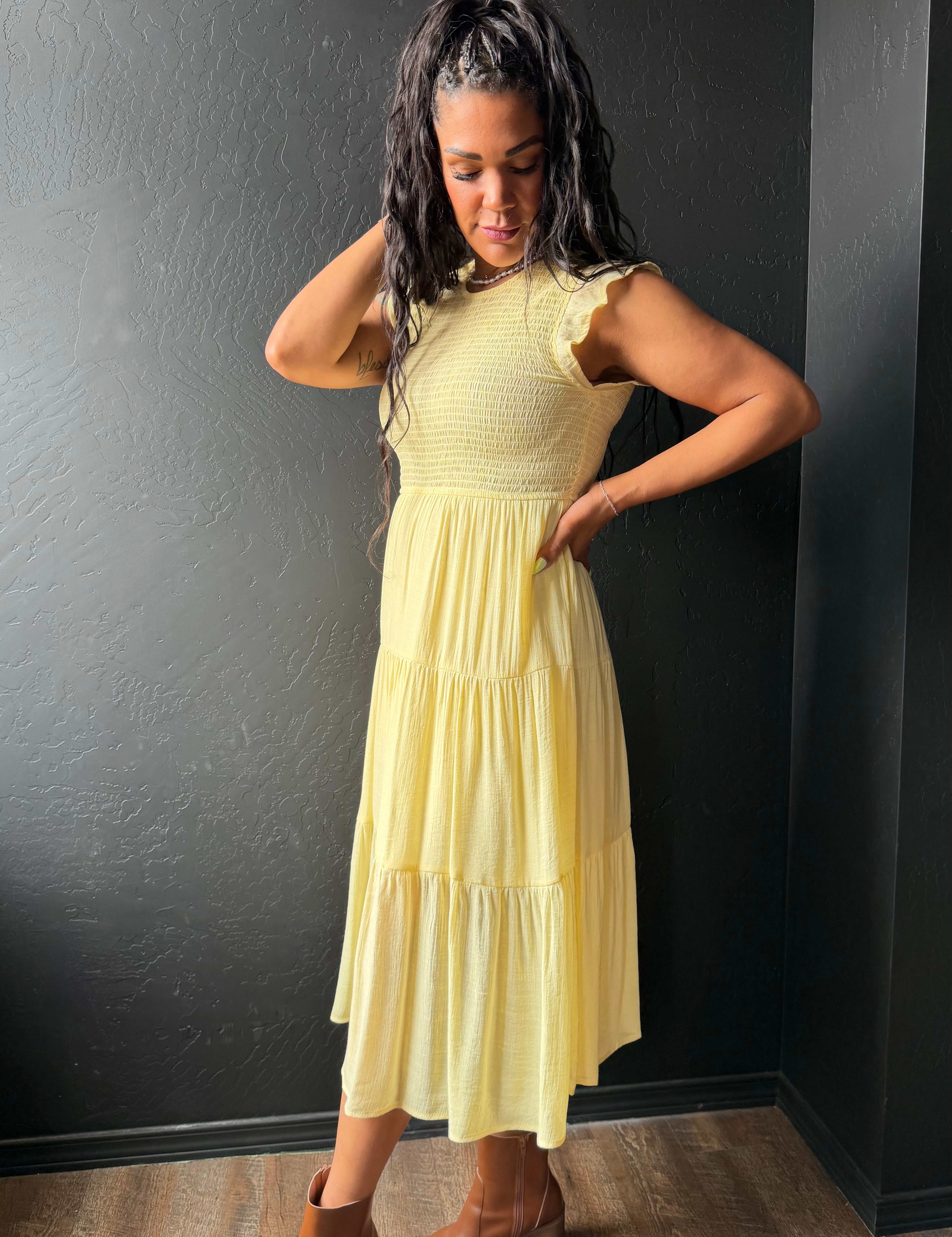 Woman wearing a yellow dress against a dark wall