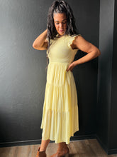 Woman wearing a yellow dress against a dark wall