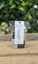 Ewe Creek Farm Co. car diffuser with a label on a woven surface with greenery in the background
