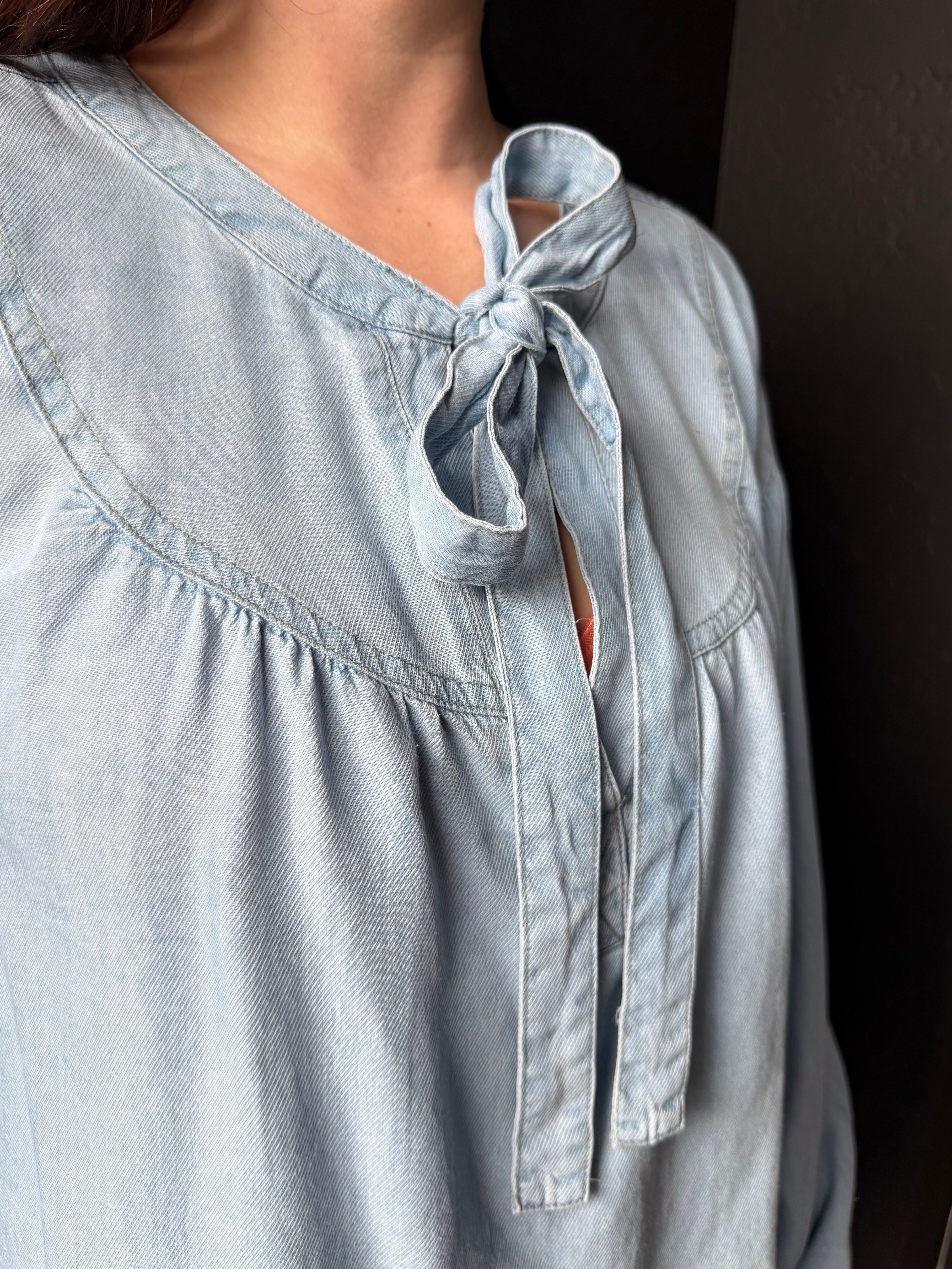 Light blue blouse with a tie detail on a dark background