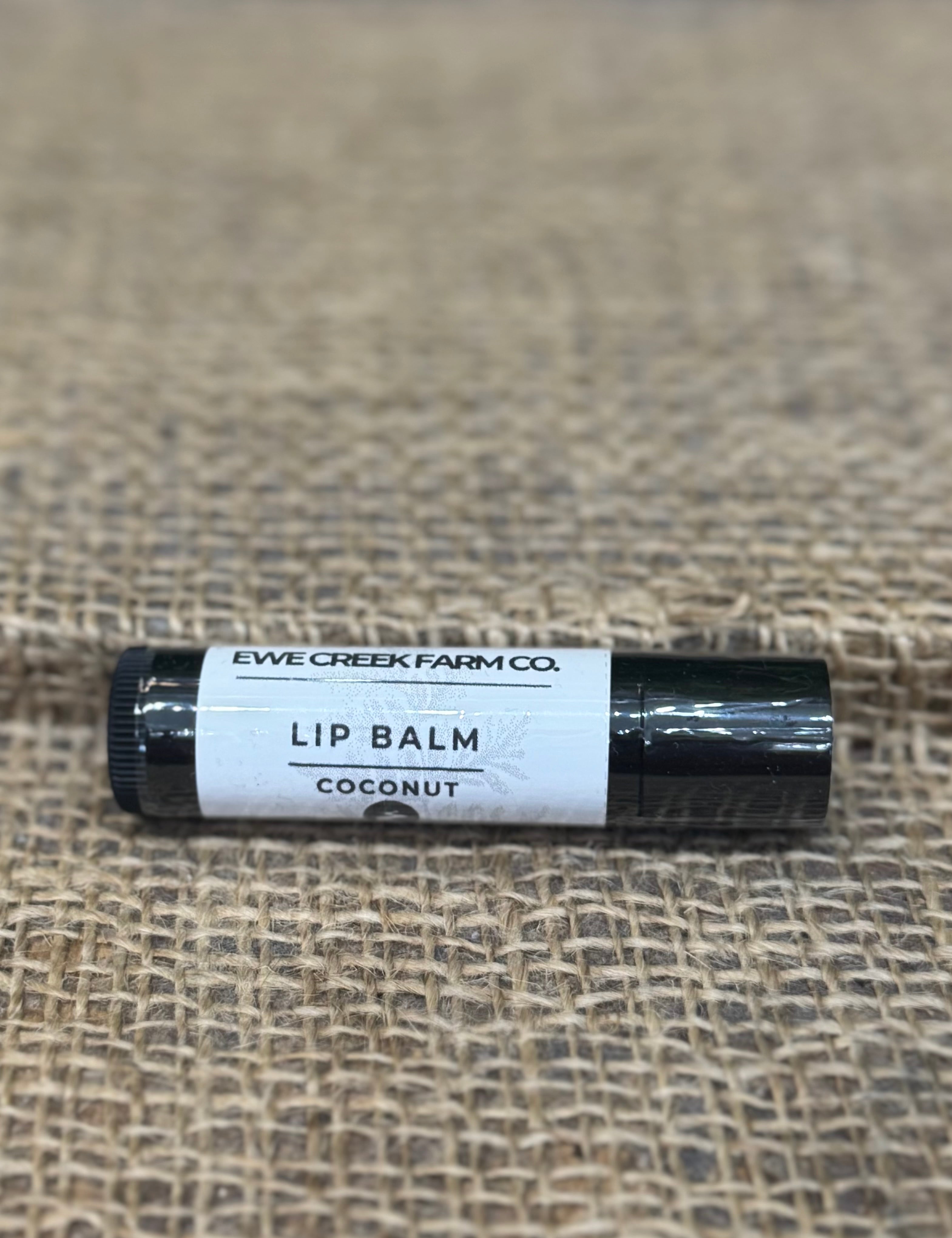 Lip balm tube labeled 'Ewe Creek Farm Co.' on a textured surface