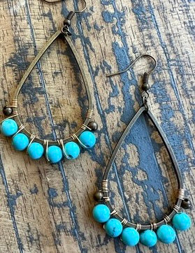 Turquoise beaded earrings on a textured wooden surface
