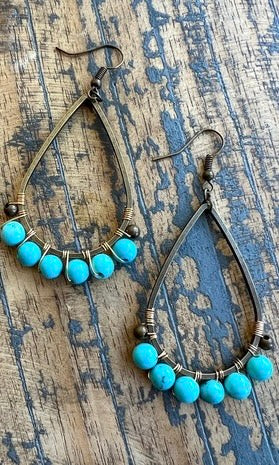 Turquoise beaded earrings on a textured wooden surface