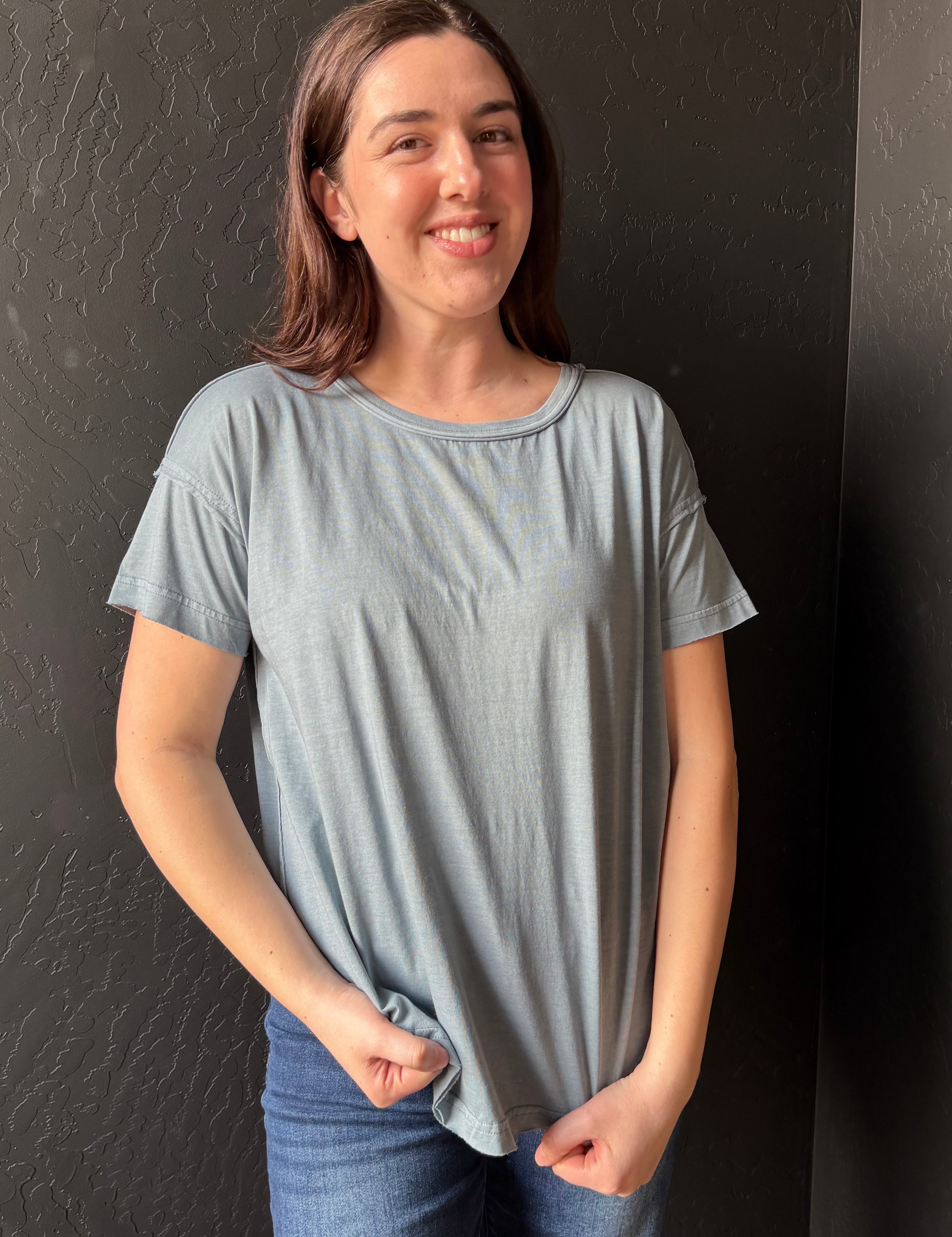 Woman wearing a light blue t-shirt against a dark background