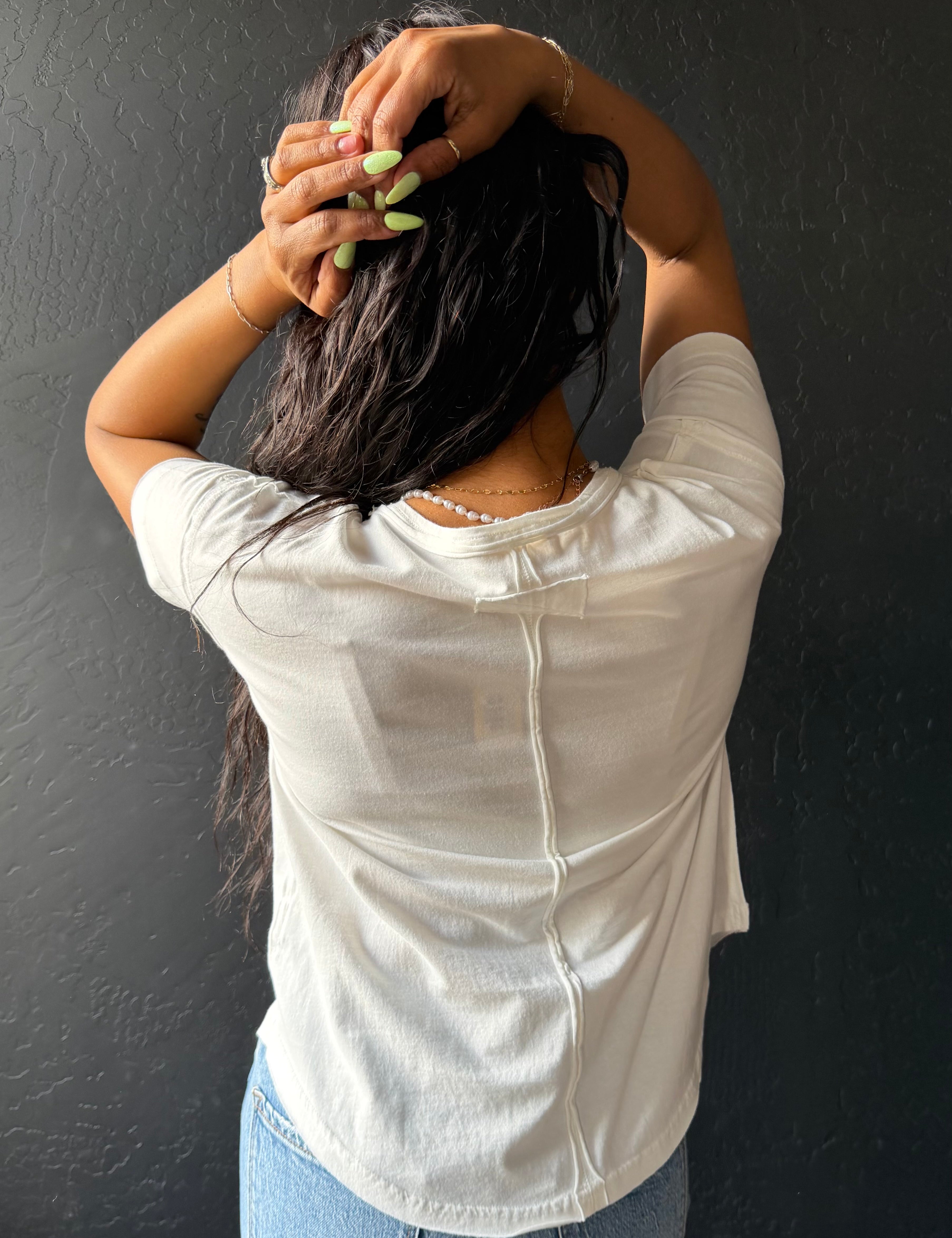 Person wearing a white shirt against a dark wall