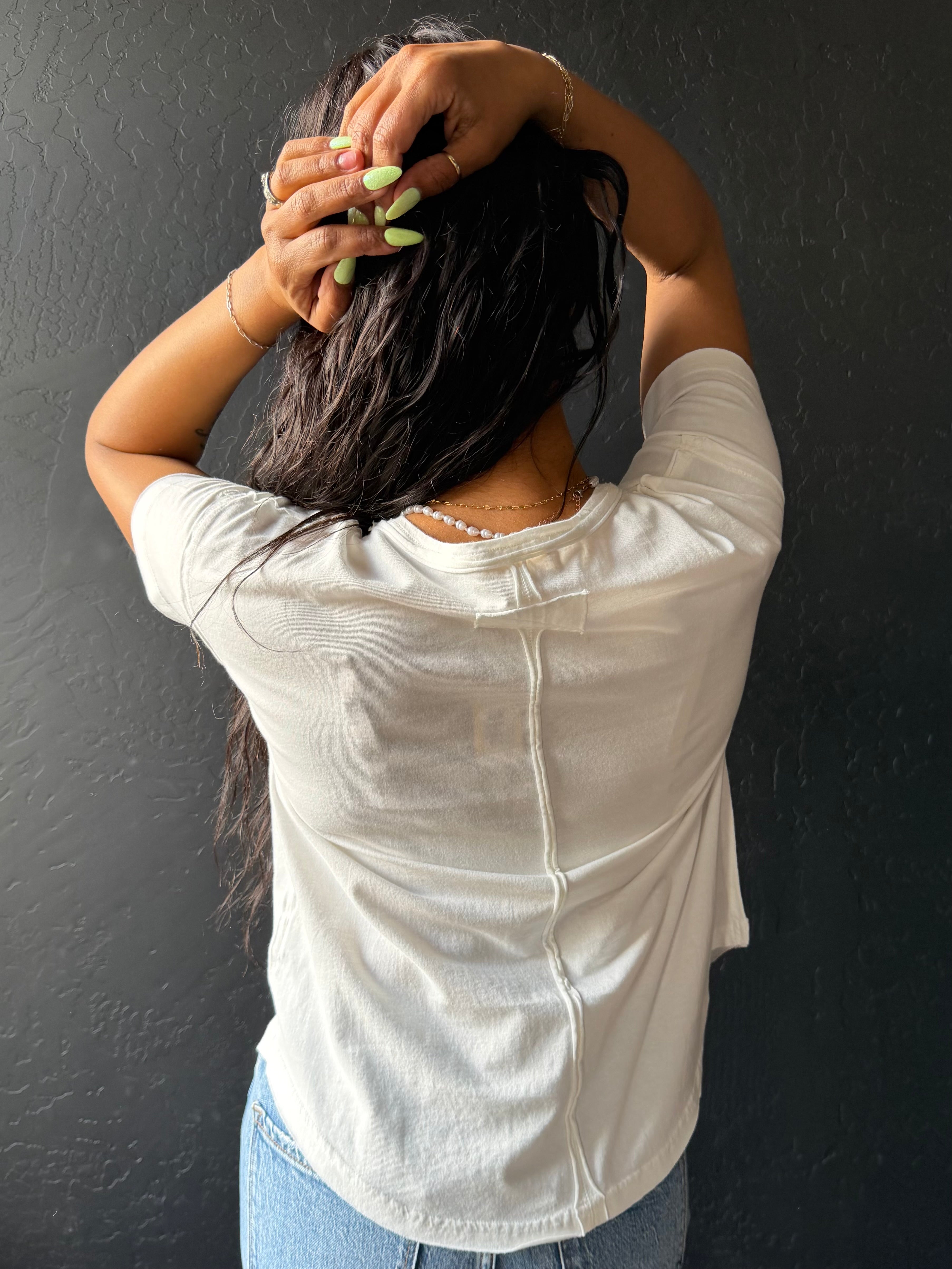 Person wearing a white shirt against a dark wall