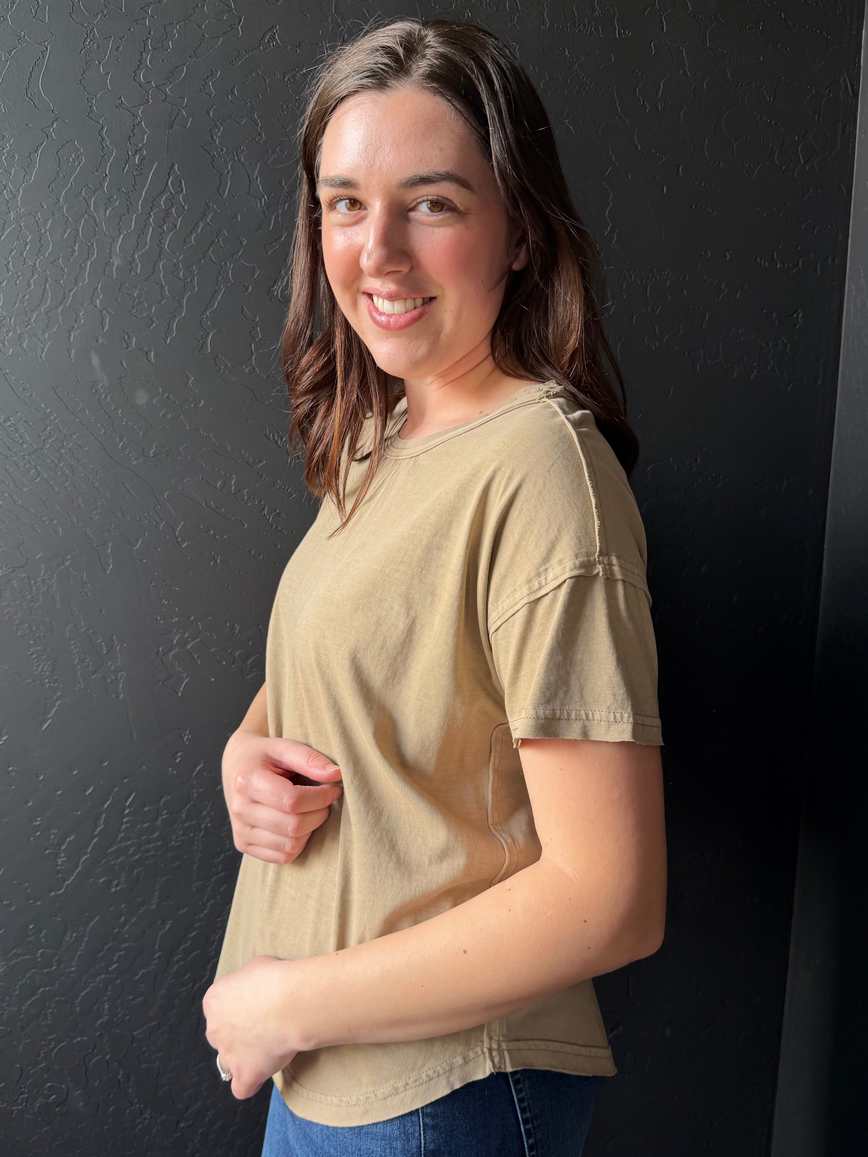 Woman wearing a beige t-shirt against a black background