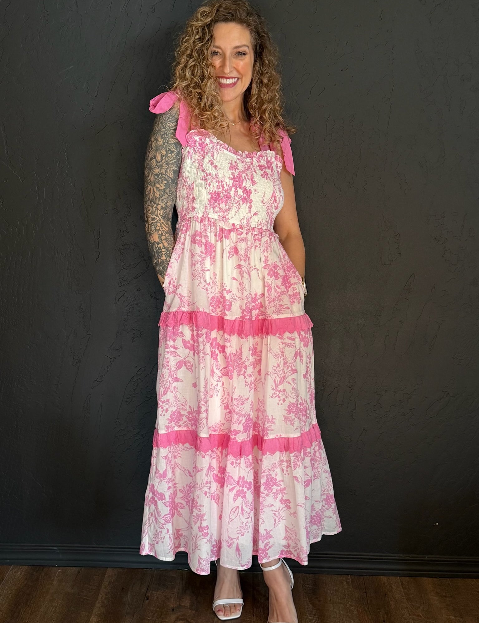 Woman wearing a pink and white floral dress against a black background