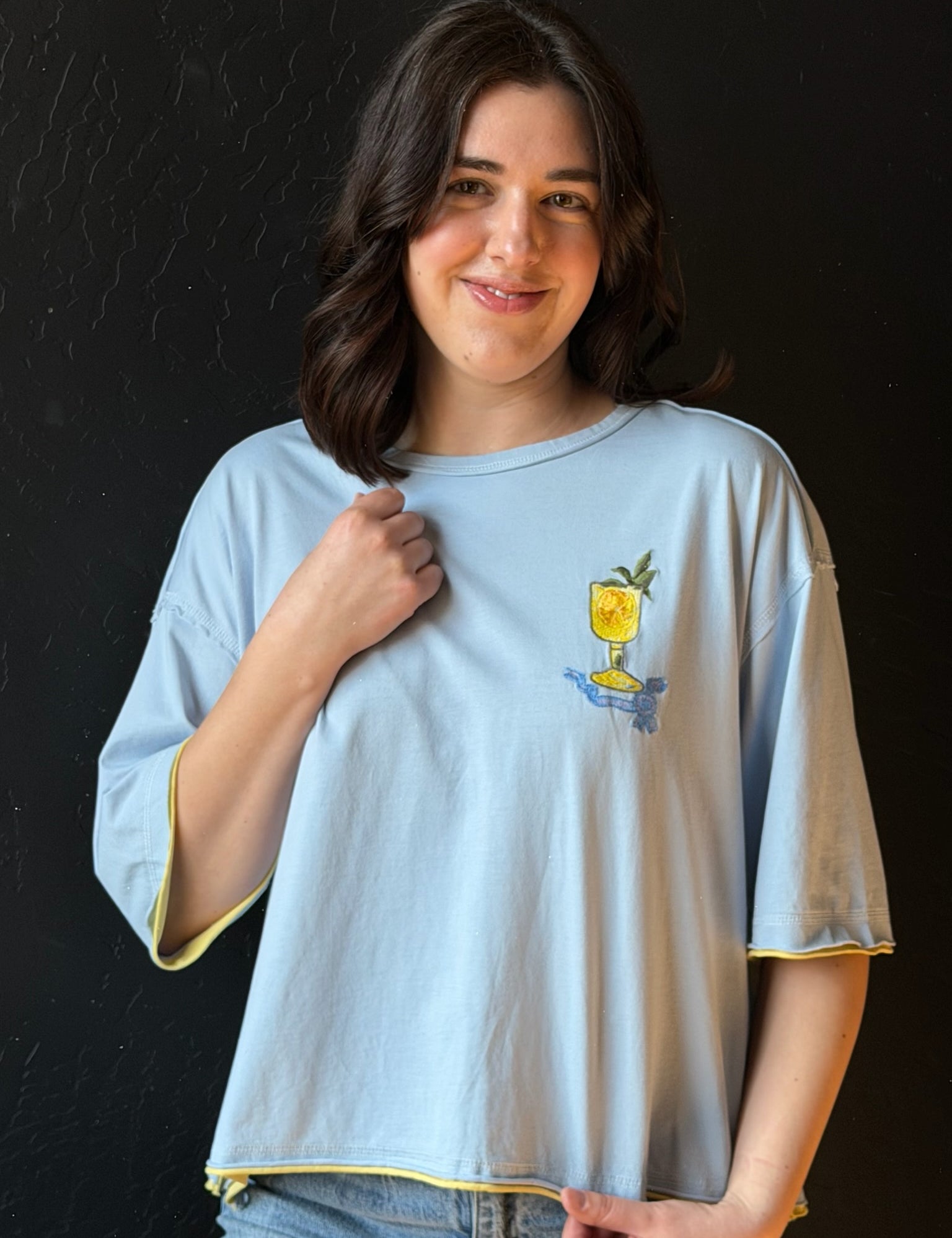 Woman wearing a light blue t-shirt with a graphic design on a black background