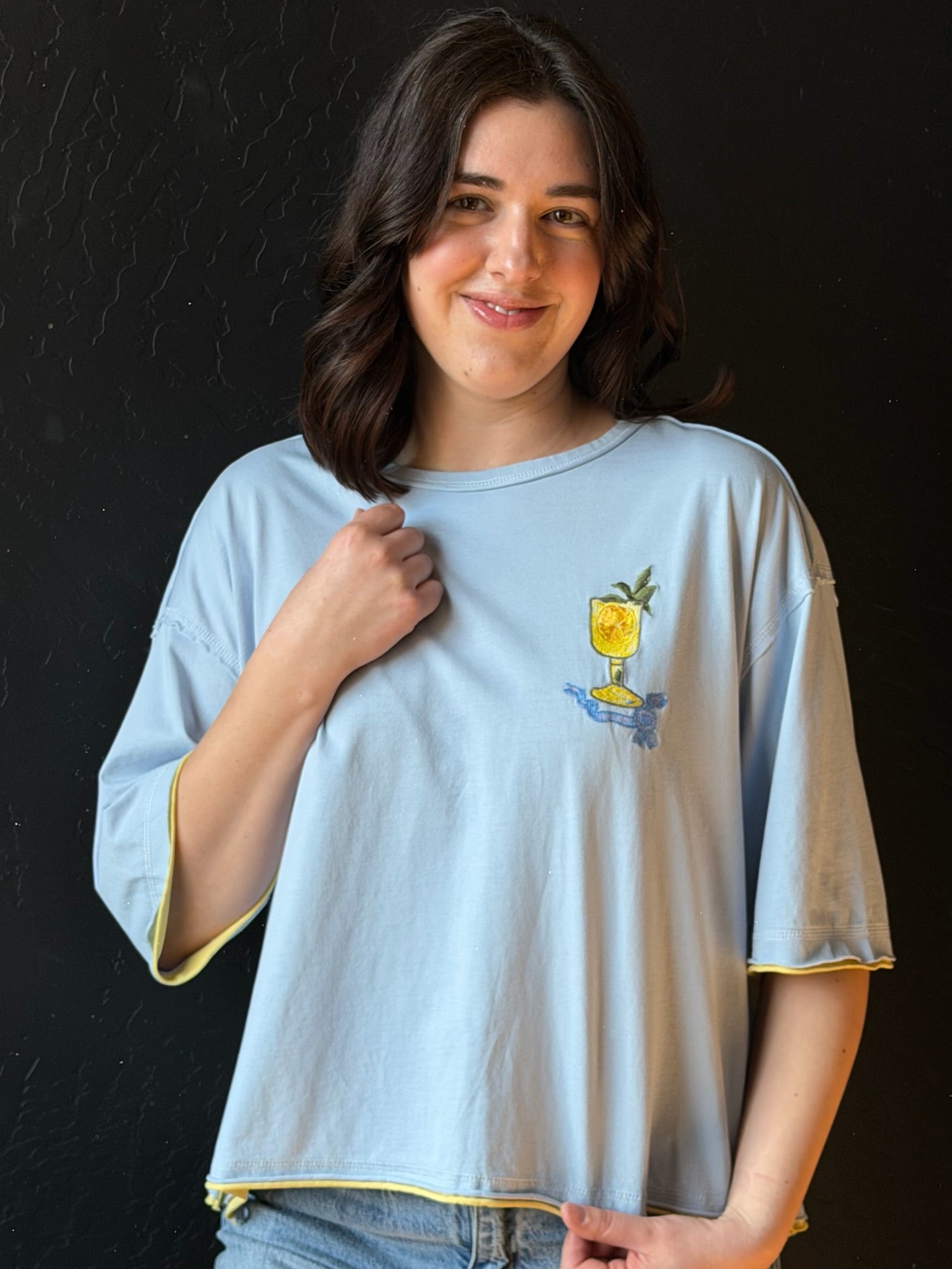 Woman wearing a light blue t-shirt with a graphic design on a black background