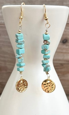 Turquoise beaded earrings with gold accents on a white mannequin bust.
