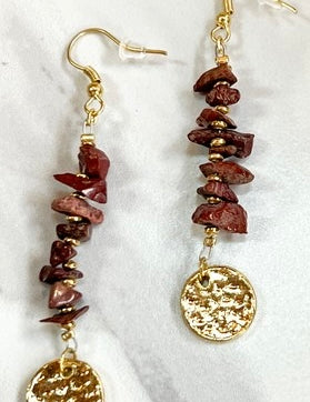 Pair of gold and brown beaded earrings on a white marble surface