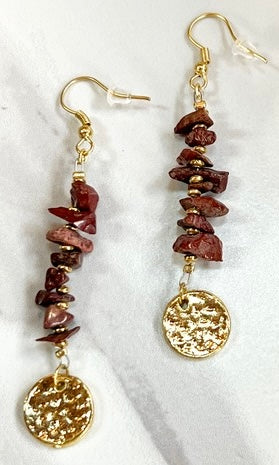 Pair of gold and brown beaded earrings on a white marble surface