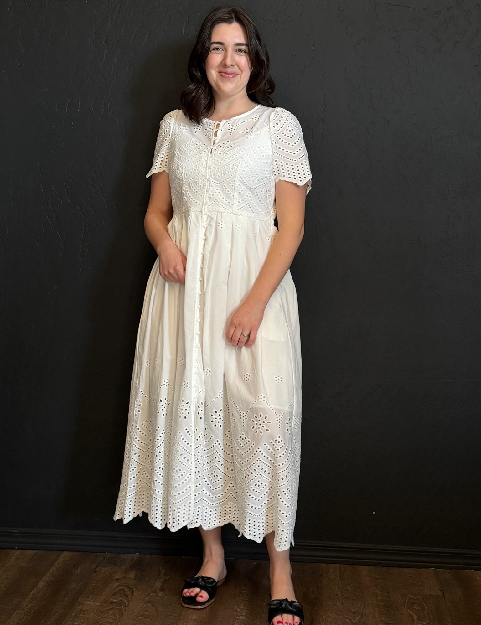 Woman wearing a white lace dress against a black background