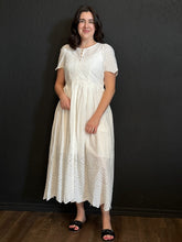 Woman wearing a white lace dress against a black background