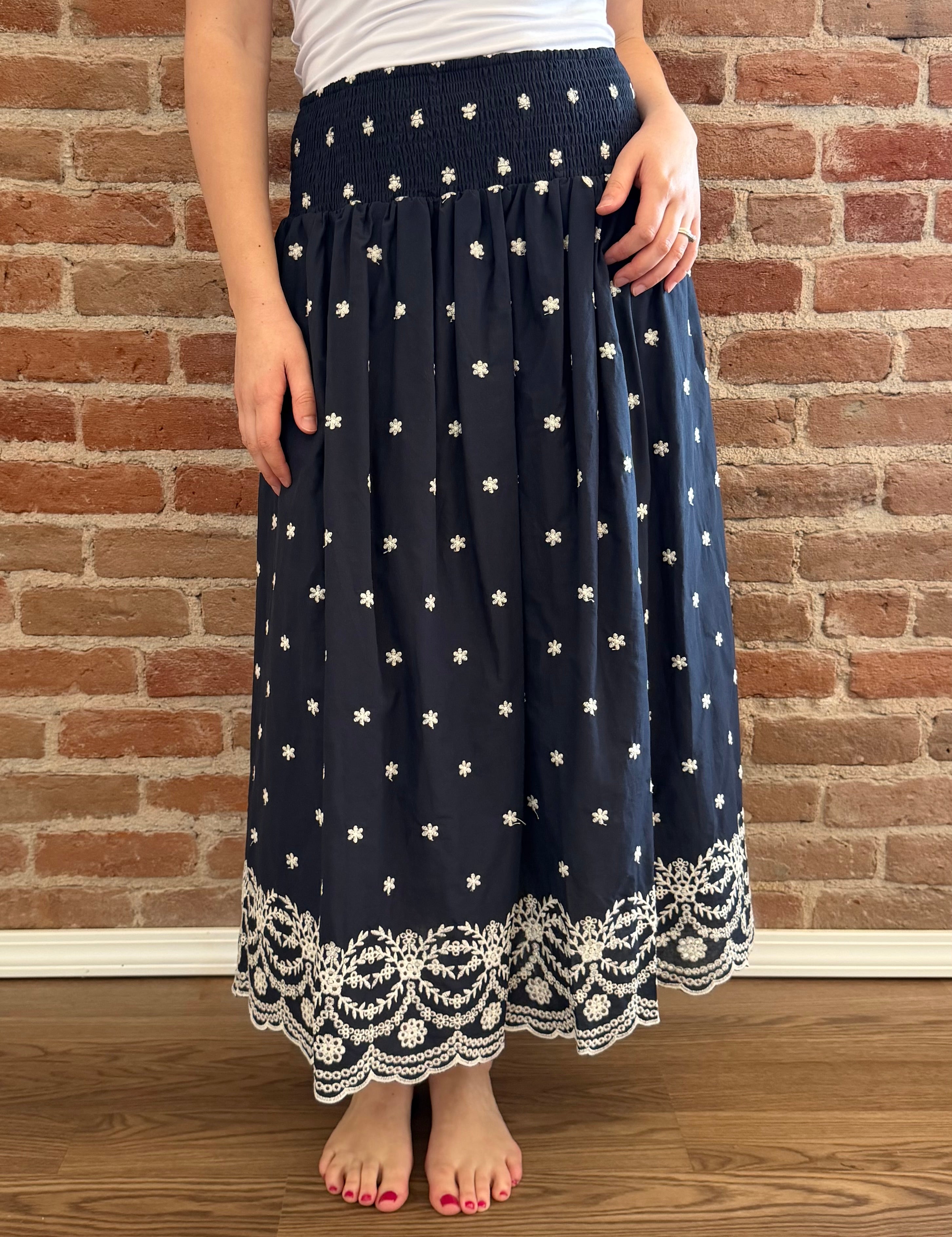Person wearing a navy blue skirt with white star patterns against a brick wall.