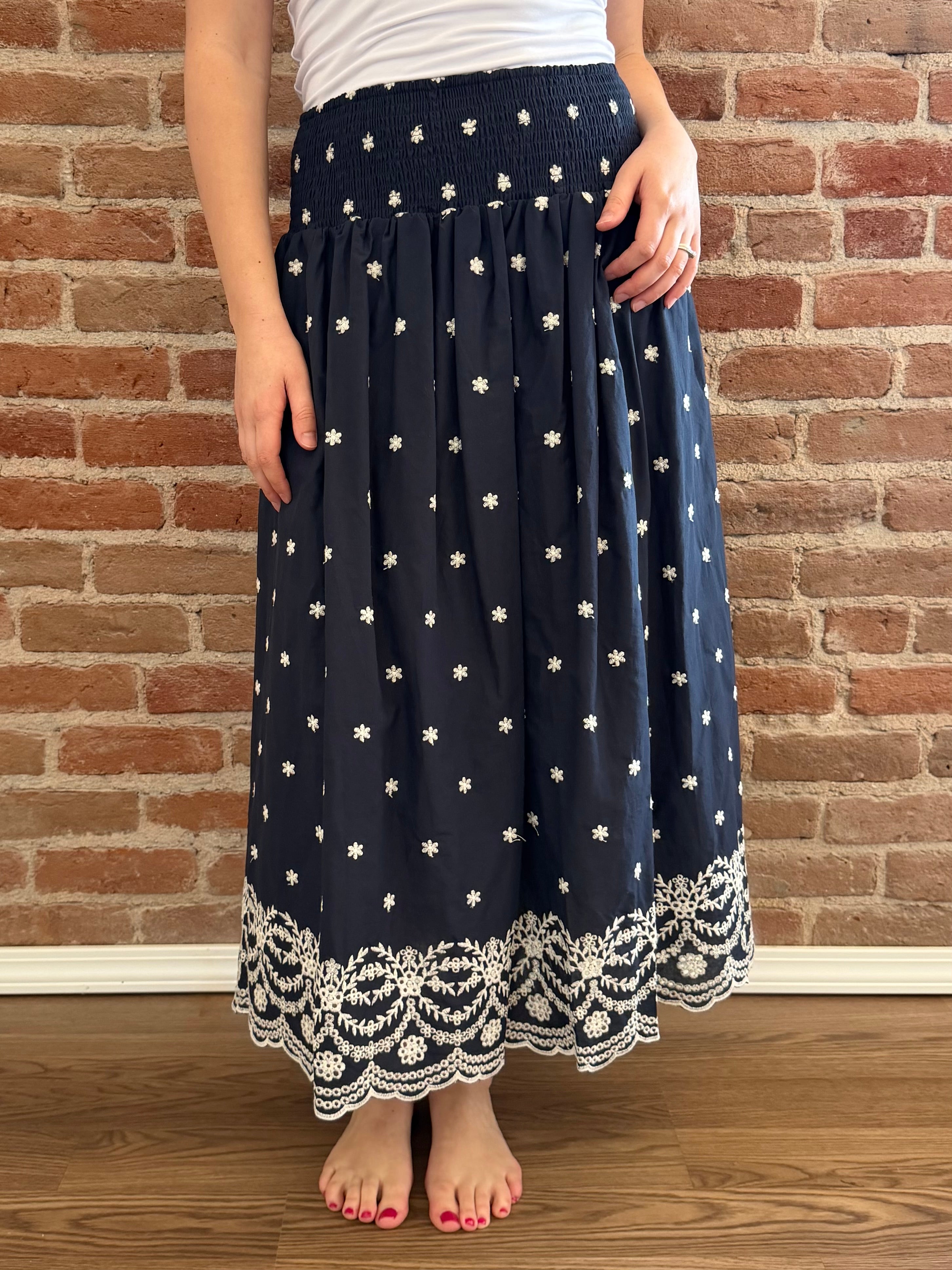 Person wearing a navy blue skirt with white star patterns against a brick wall.