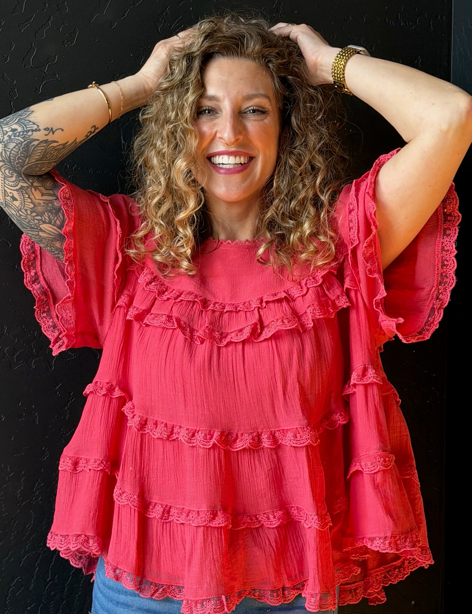 Woman wearing a pink ruffled blouse against a black background