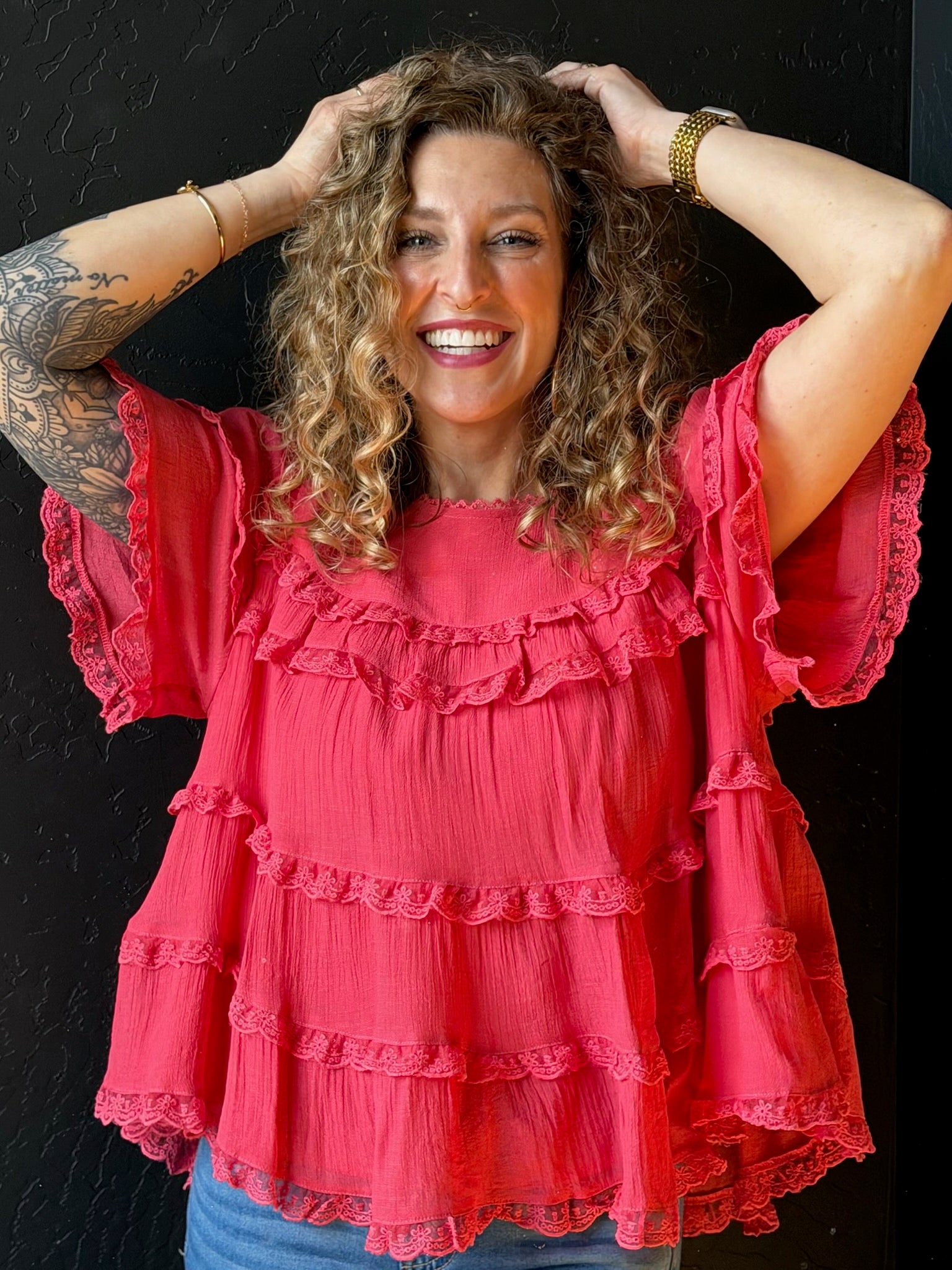 Woman wearing a pink ruffled blouse against a black background