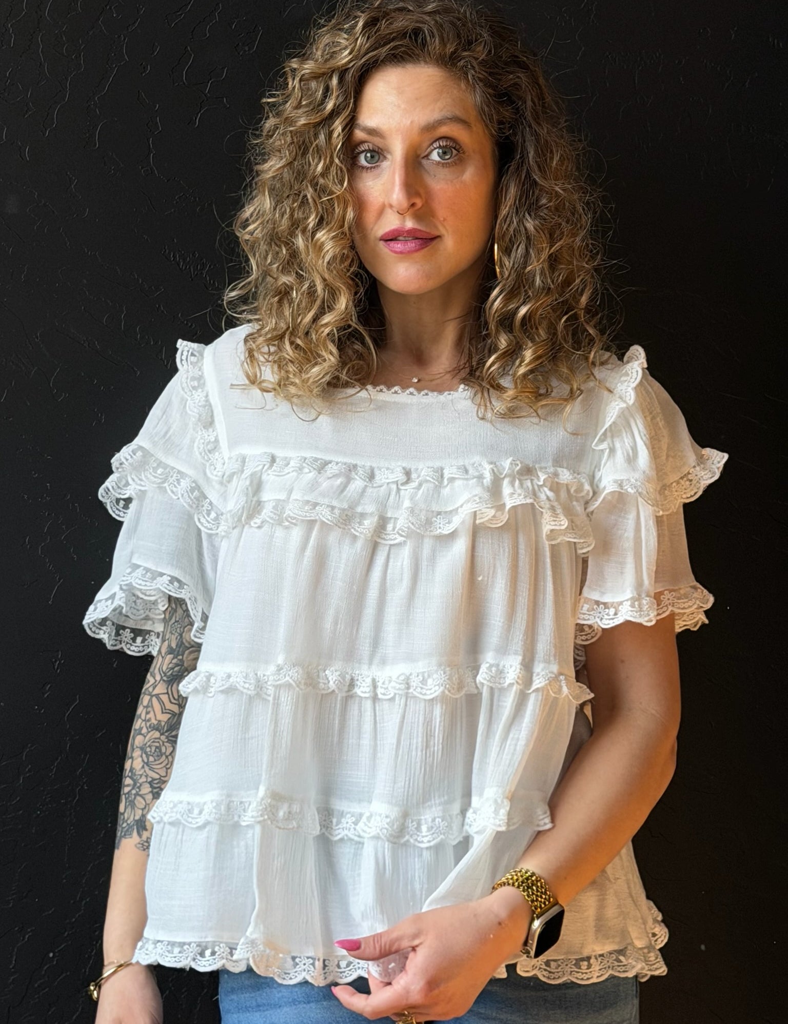 Woman wearing a white ruffled blouse against a black background