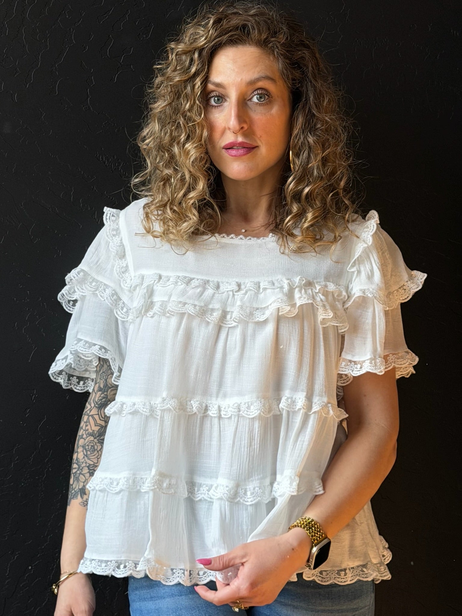 Woman wearing a white ruffled blouse against a black background