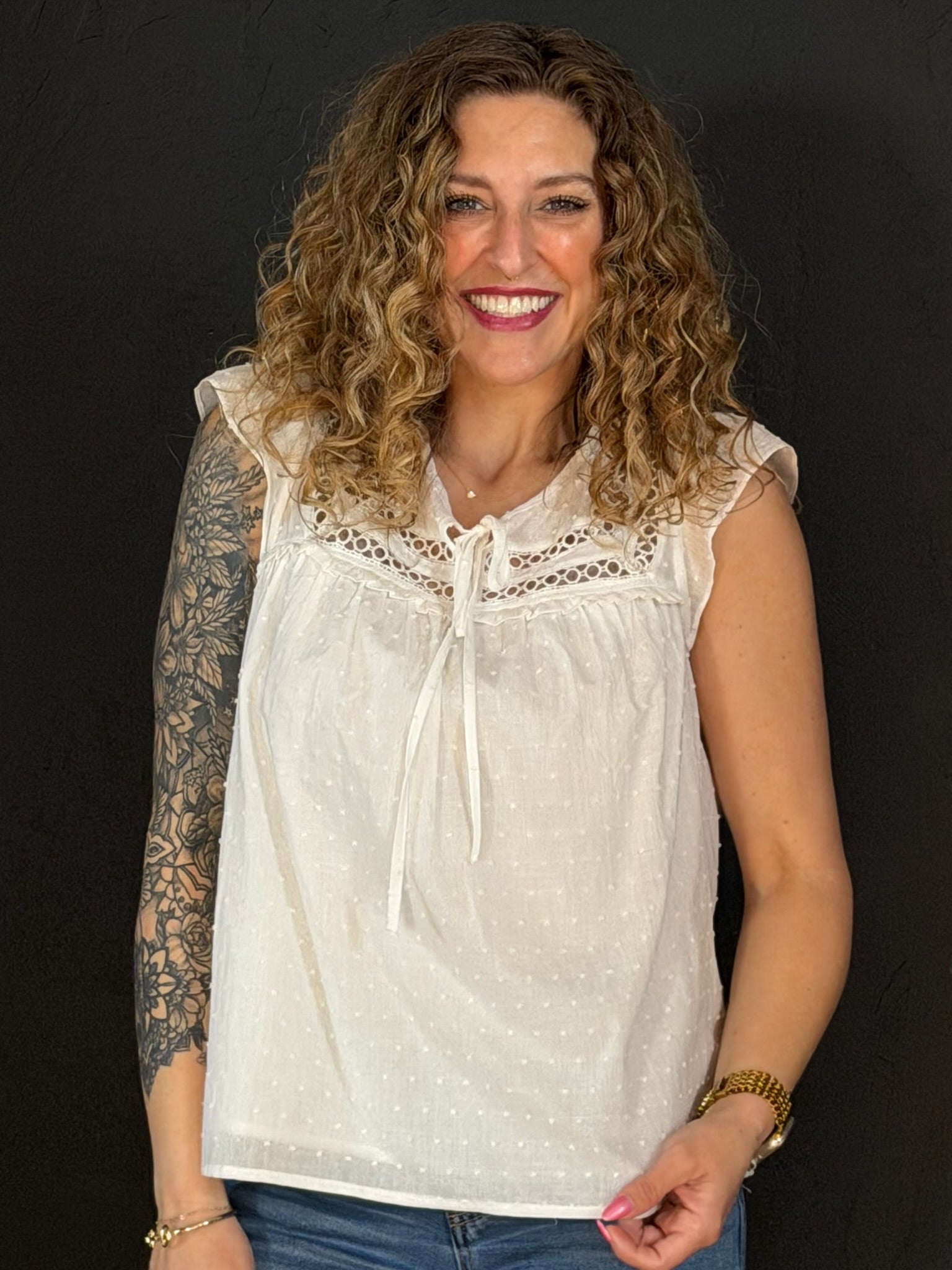 Woman wearing a white lace top against a black background