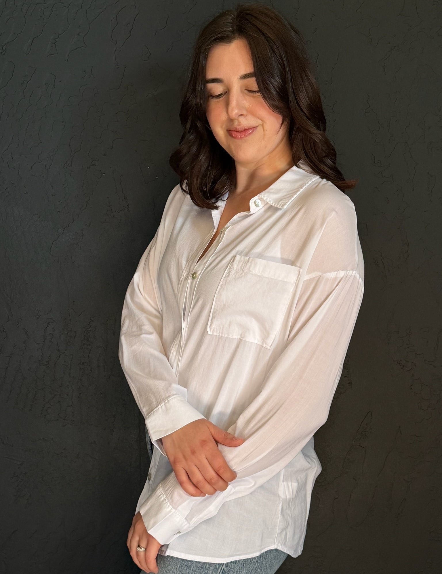 Woman wearing a white blouse against a dark background