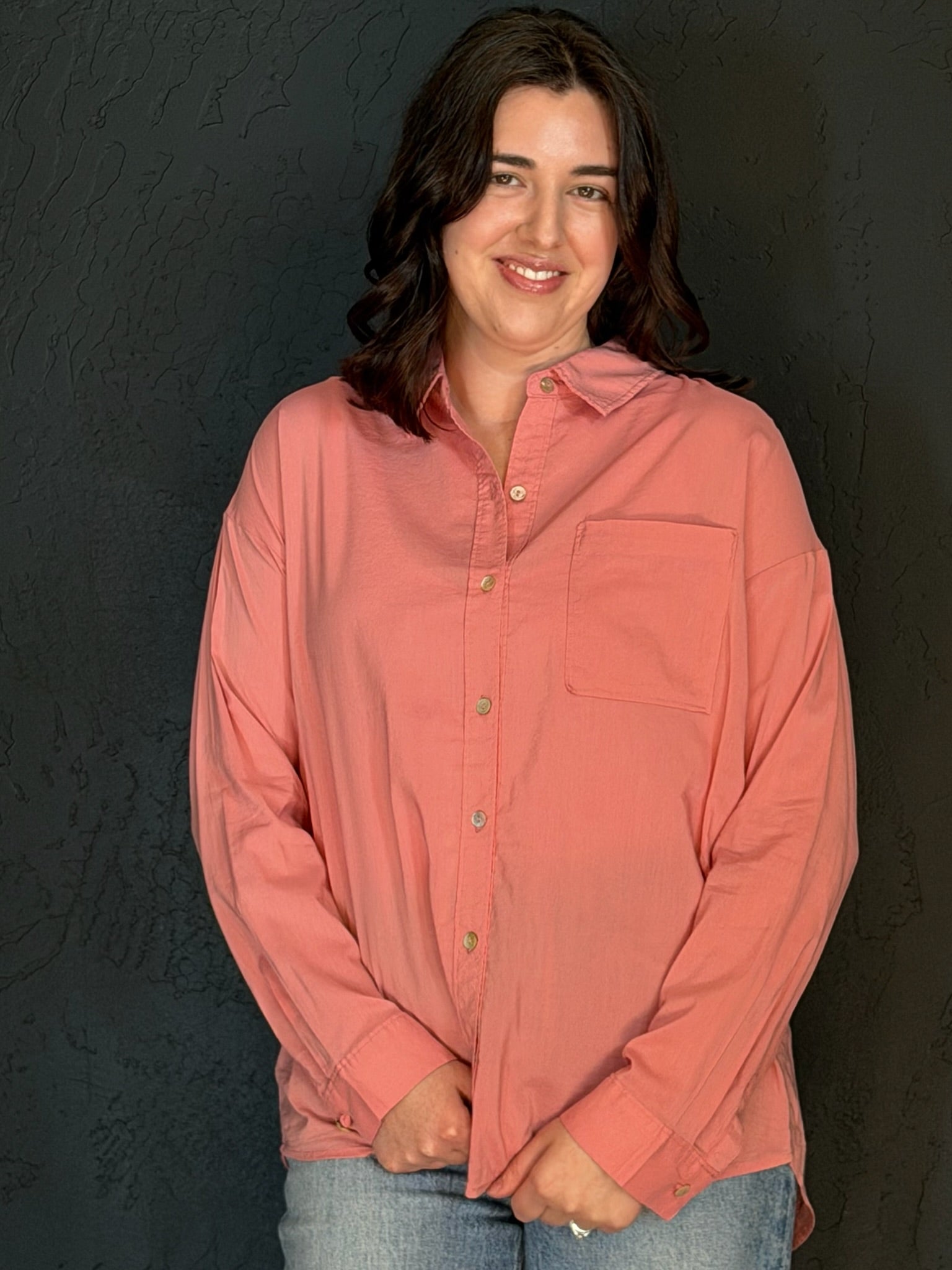 Person wearing a pink shirt against a black background