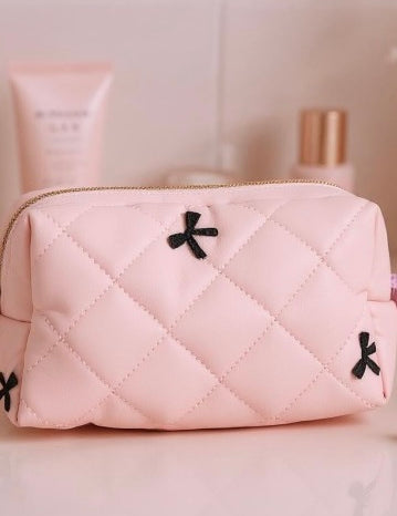 Pink quilted pouch with black accents on a light pink background