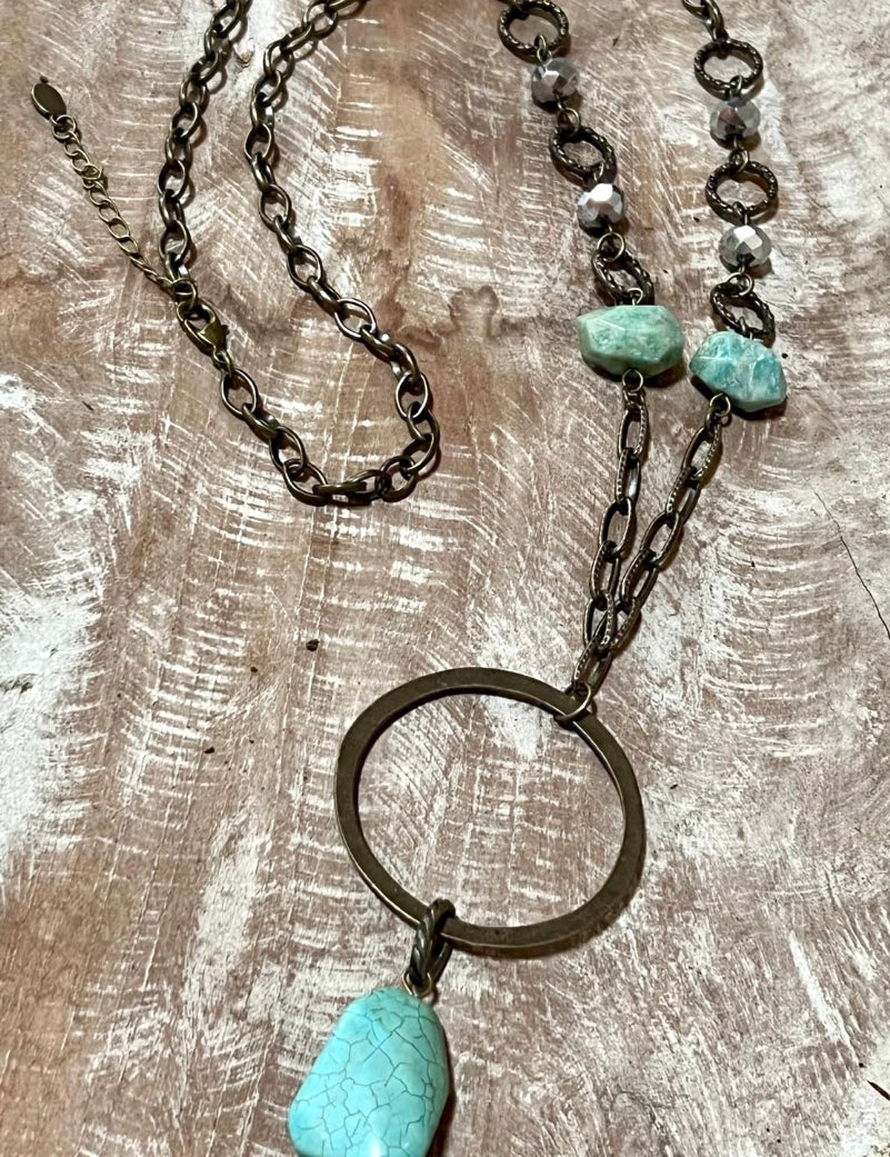 A long necklace with a chain link chain and a turquoise beaded pendant with a lobster claw closure.