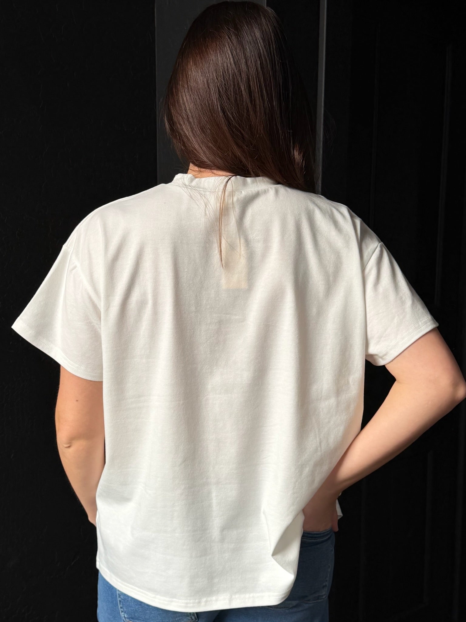 Person wearing a white t-shirt against a black background
