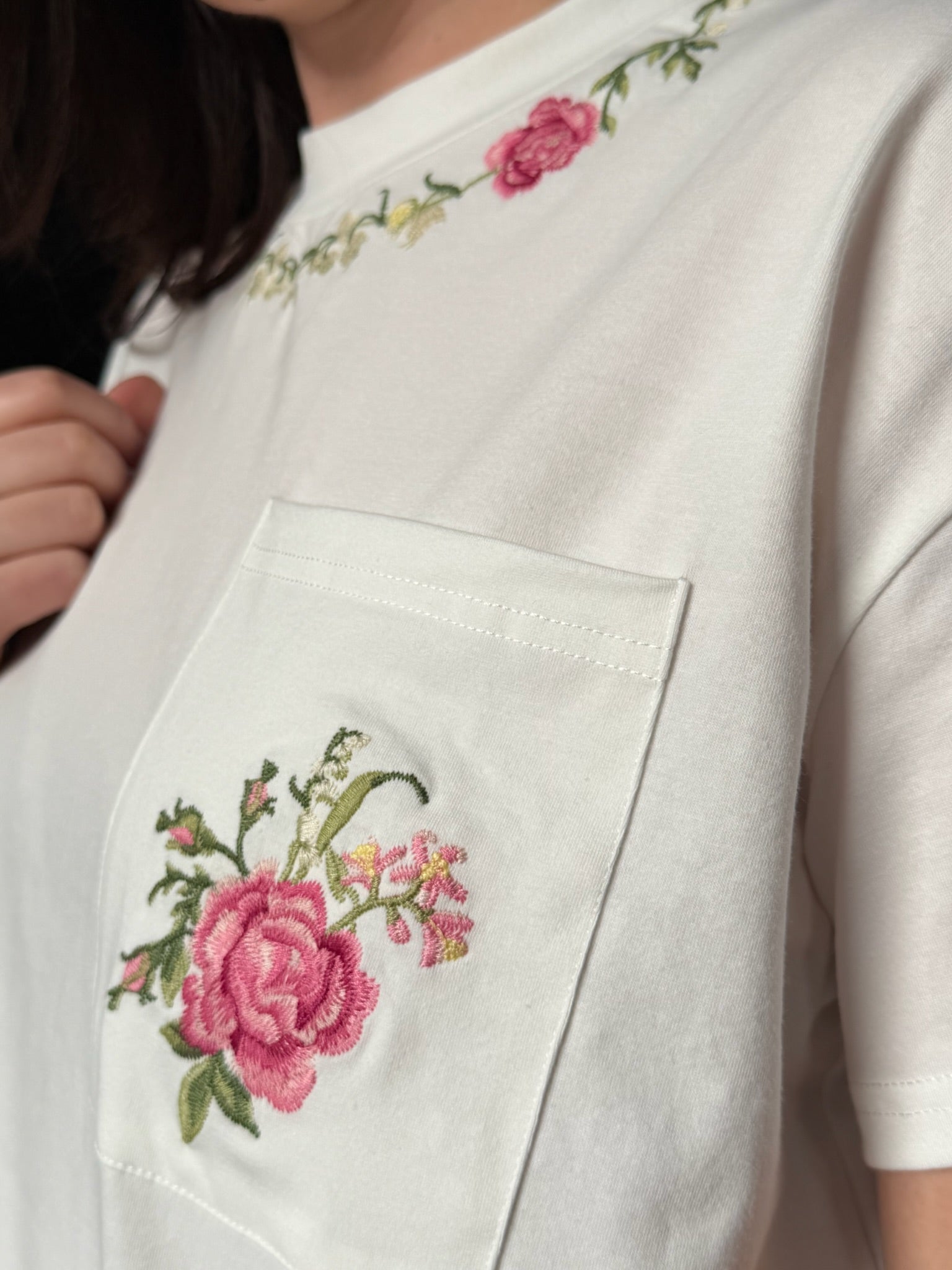 White garment with floral embroidery on a pocket