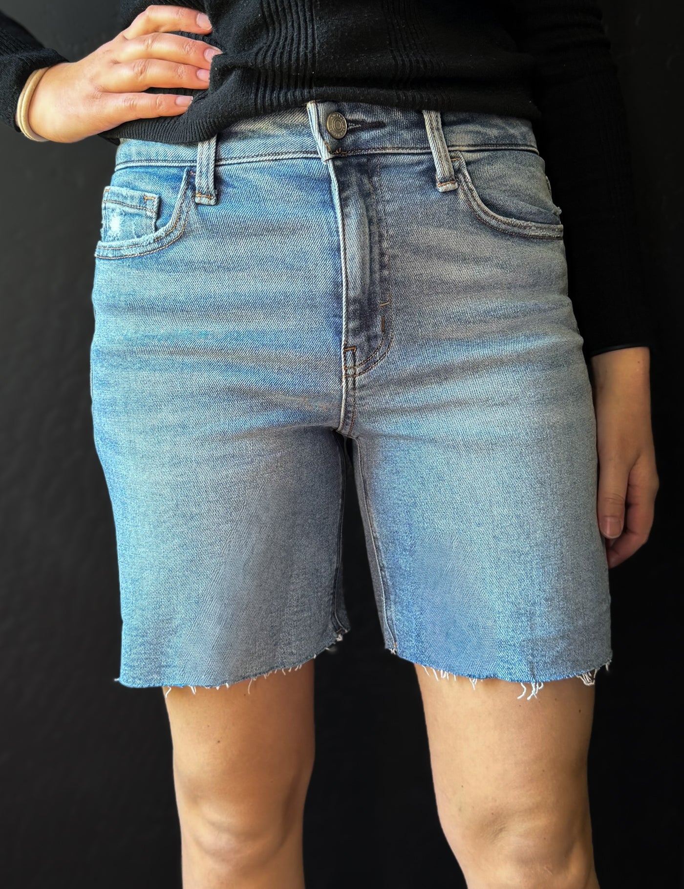 Person wearing blue denim shorts on a black background