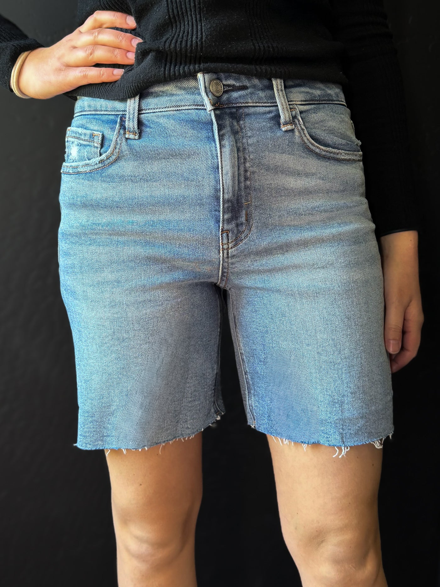 Person wearing blue denim shorts on a black background