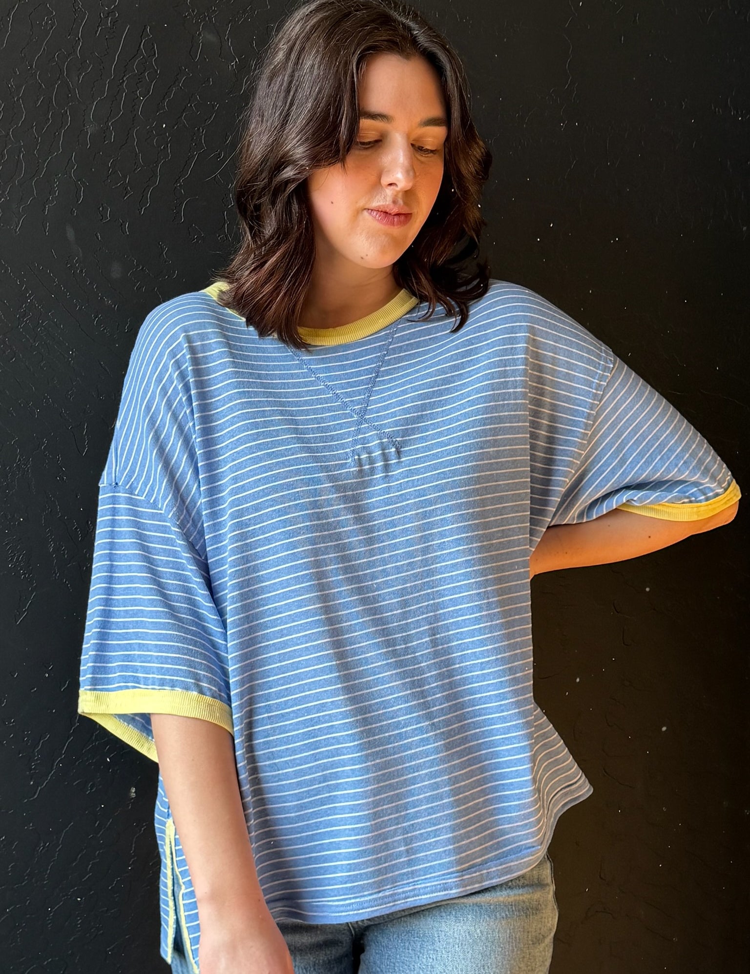Woman wearing a blue and yellow striped shirt against a black background