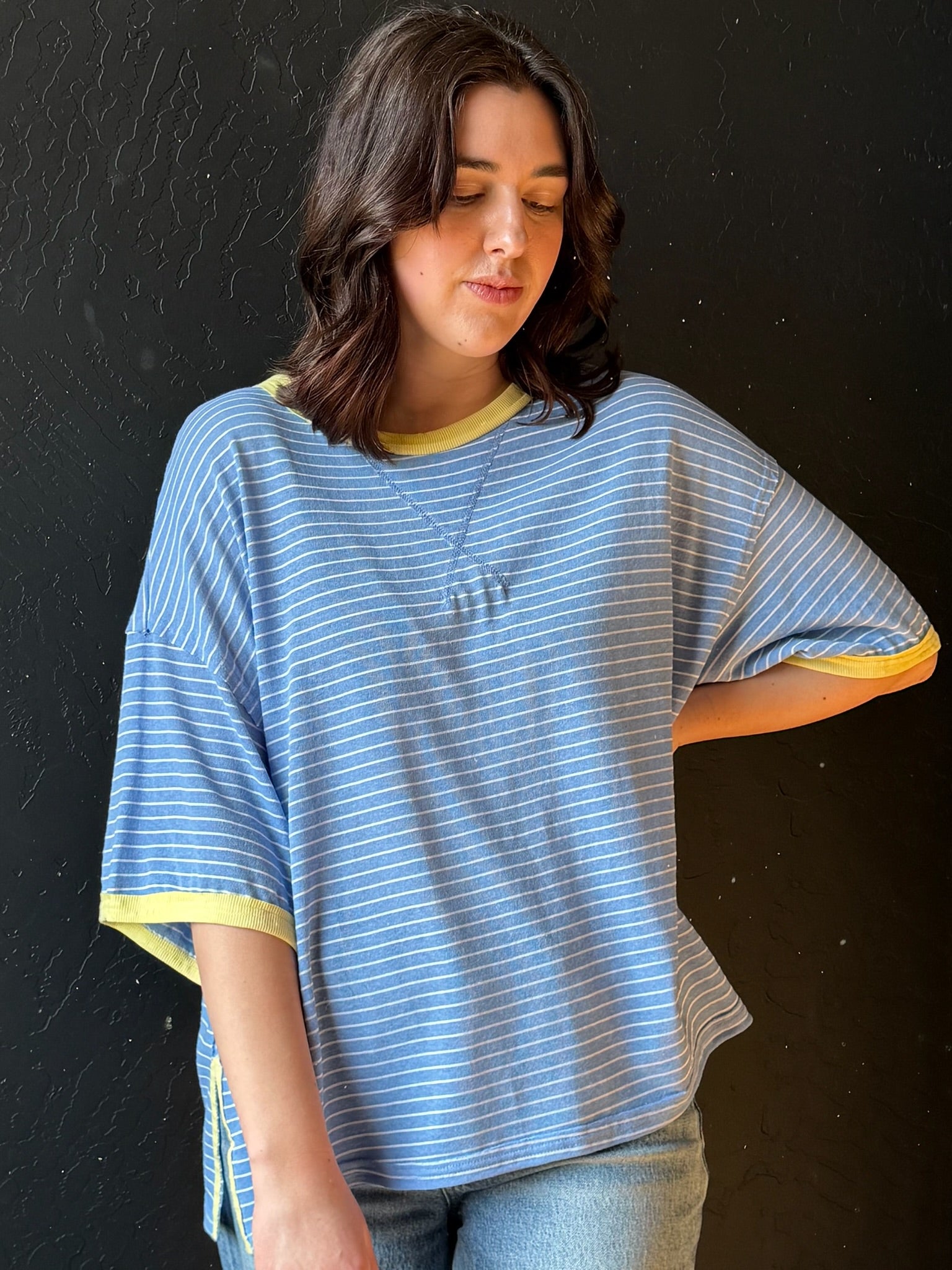Woman wearing a blue and yellow striped shirt against a black background