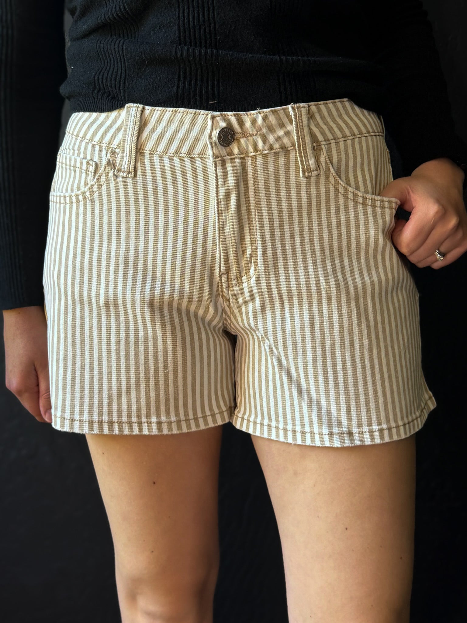 Person wearing beige and white striped shorts on a black background
