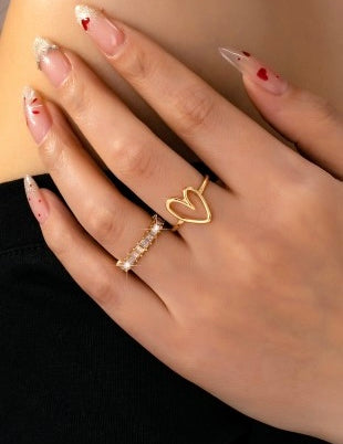 Close-up of a hand wearing gold Heart ring with intricate designs.