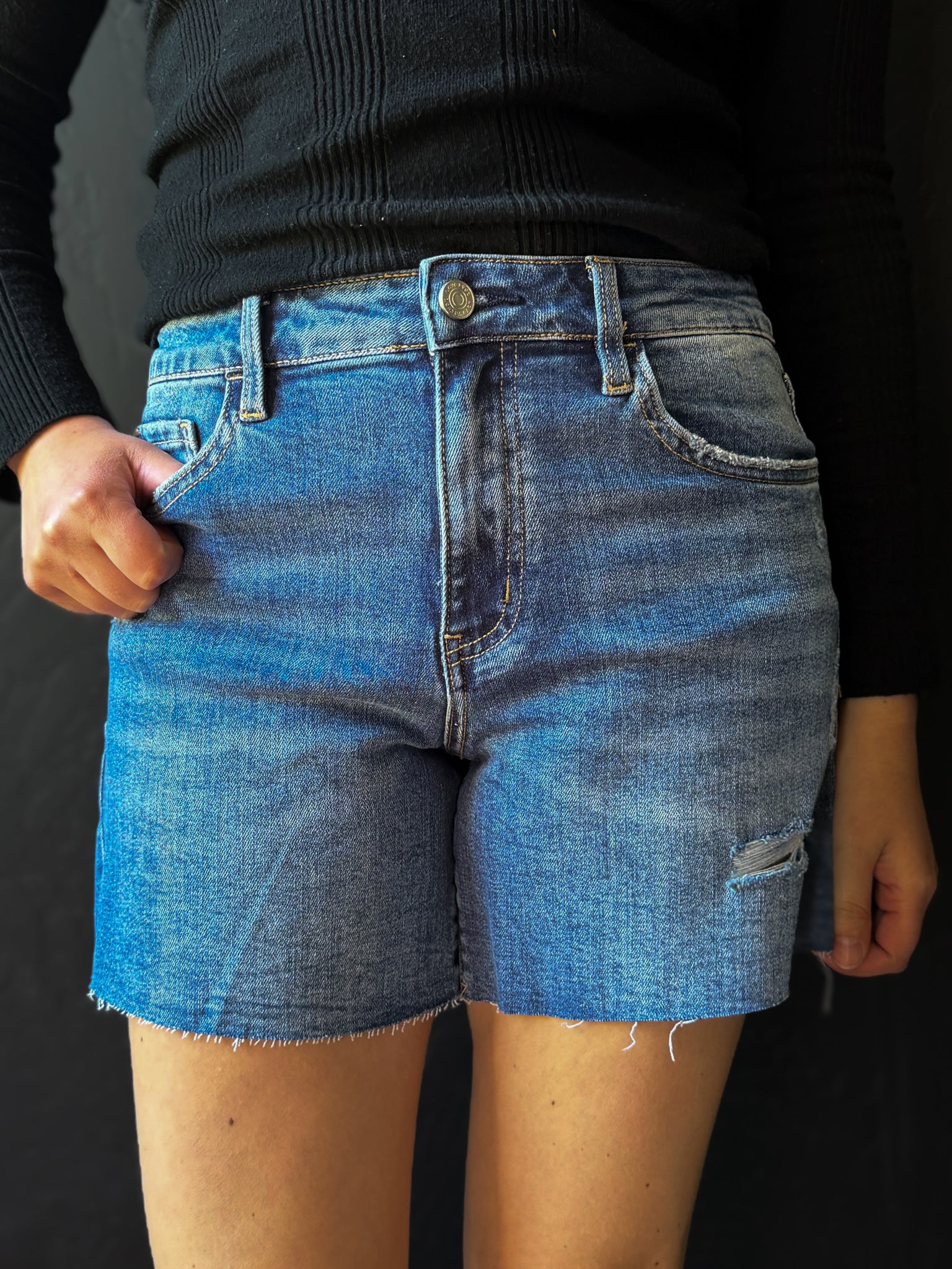 Person wearing blue denim shorts on a black background