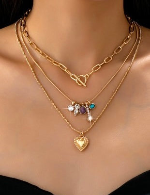 Gold necklaces with heart pendant and other charms on a mannequin.