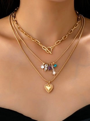 Gold necklaces with heart pendant and other charms on a mannequin.