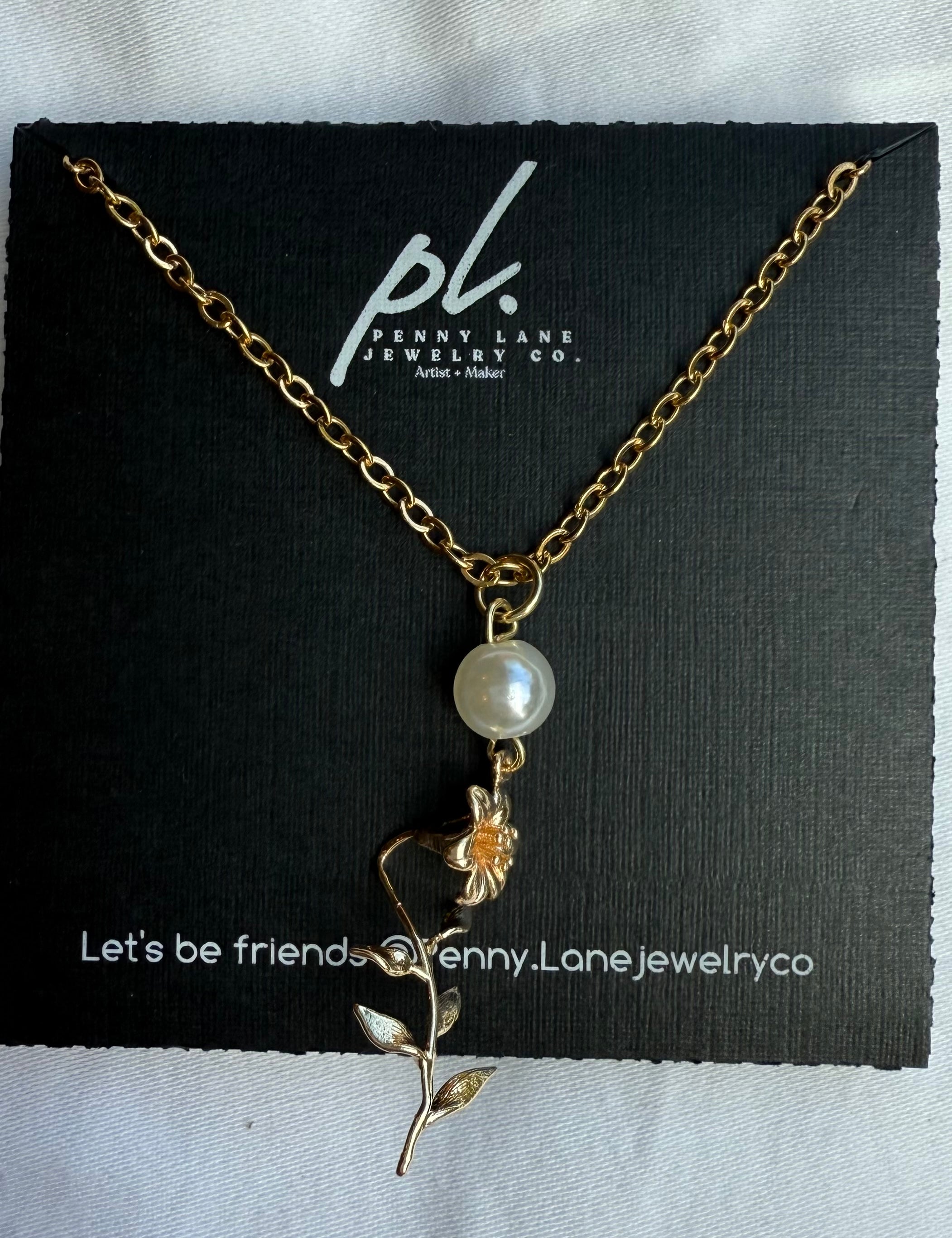 Necklace with a pearl and floral pendant on a Penny Lane Jewelry Co. card.
