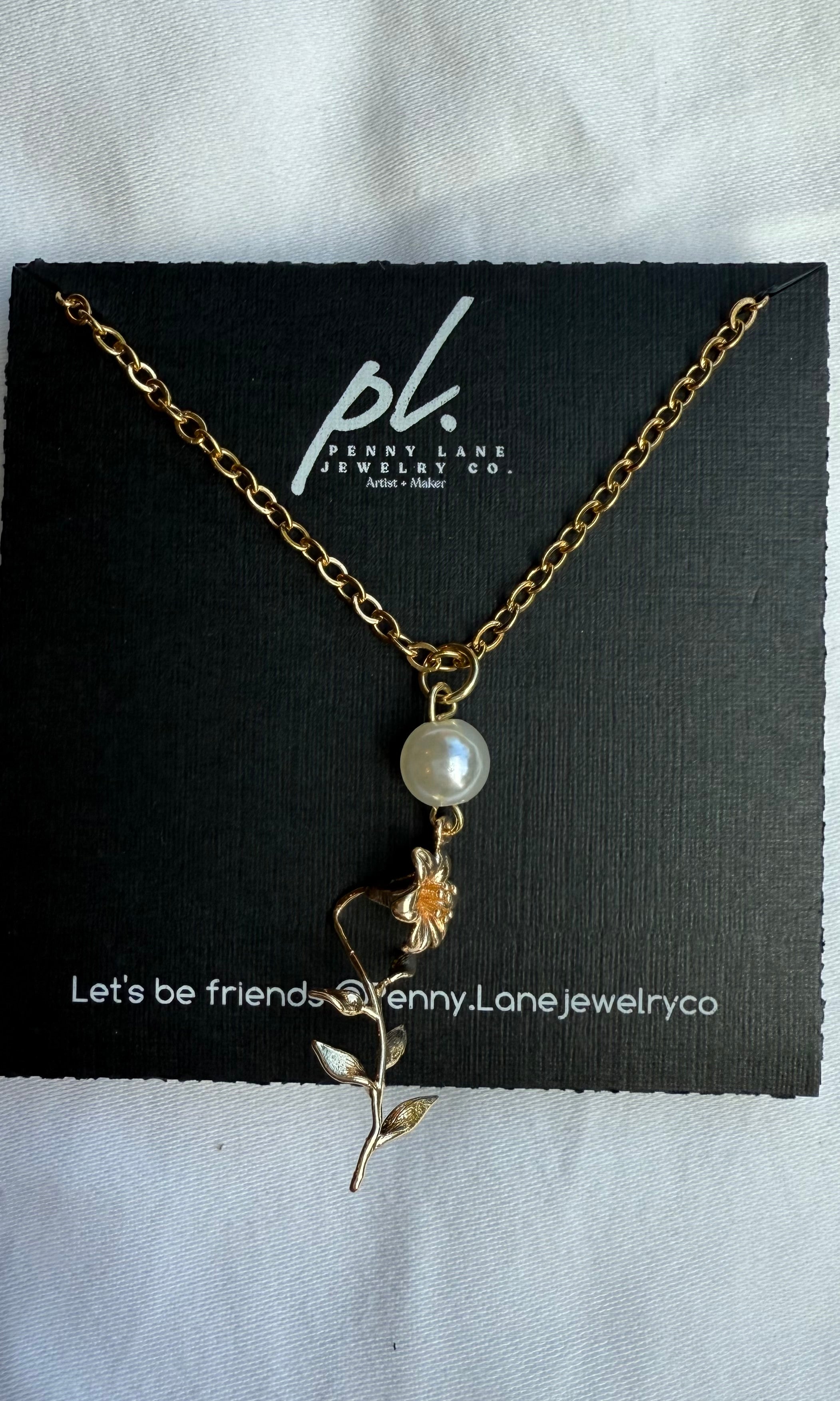 Necklace with a pearl and floral pendant on a Penny Lane Jewelry Co. card.