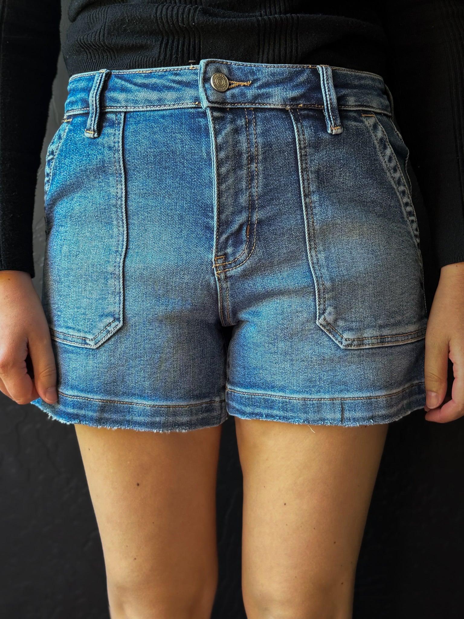 Blue denim shorts worn by a person on a black background