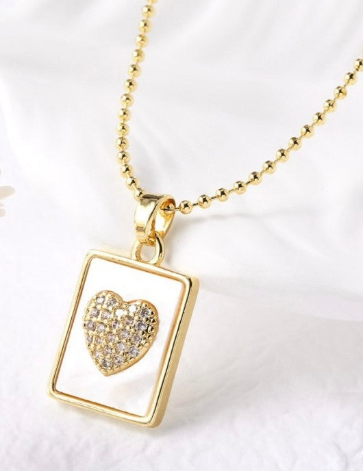 Gold necklace with a heart-shaped pendant on a white background
